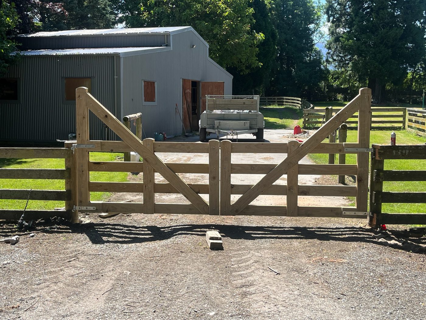 Newly built five-bar timber farm gate hung between post and rail fencing